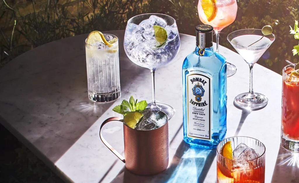 Bombay Sapphire Gun bottle with cocktails in various glasses around it.